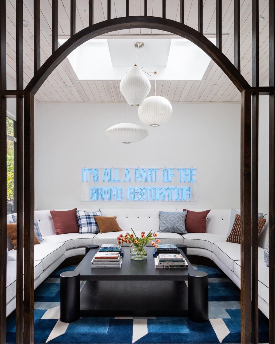 Glowing neon sign mounted over an eclectic gallery wall on a white wall