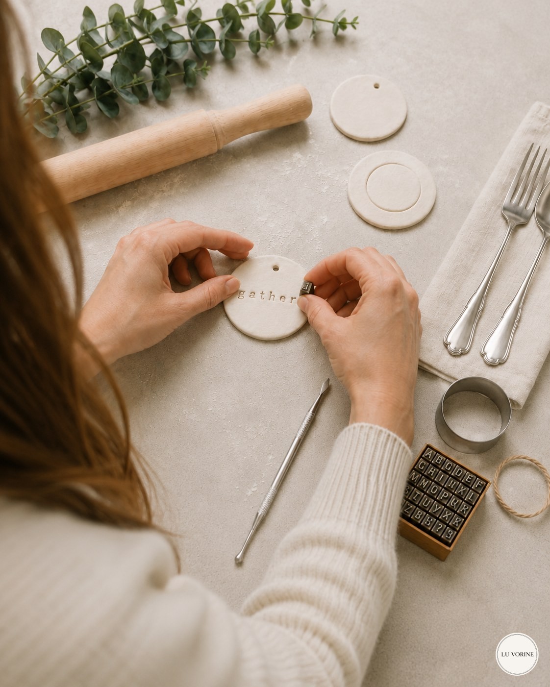 Stamping lettering into a soft clay disc while shaping a napkin ring tag