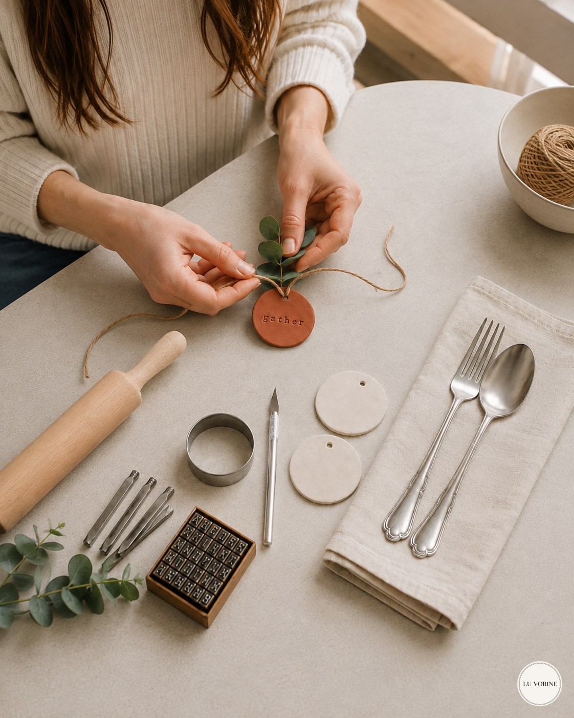 Threading twine and eucalyptus through a dried clay napkin ring tag