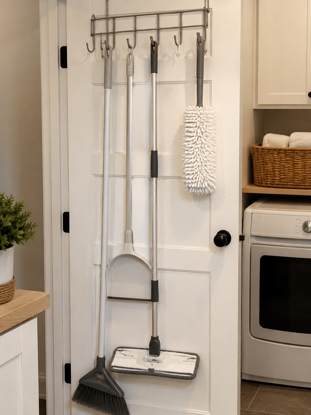 Over-the-door hook rack demonstrating dollar store bathroom organization for mops, brooms and dusters