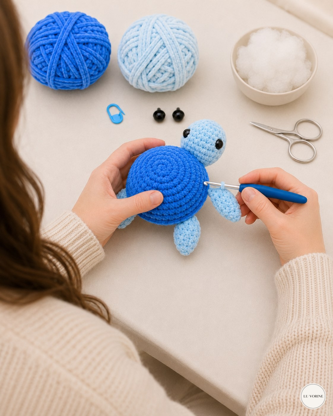 Attaching the front flippers to the no-sew plush turtle while working at a home table
