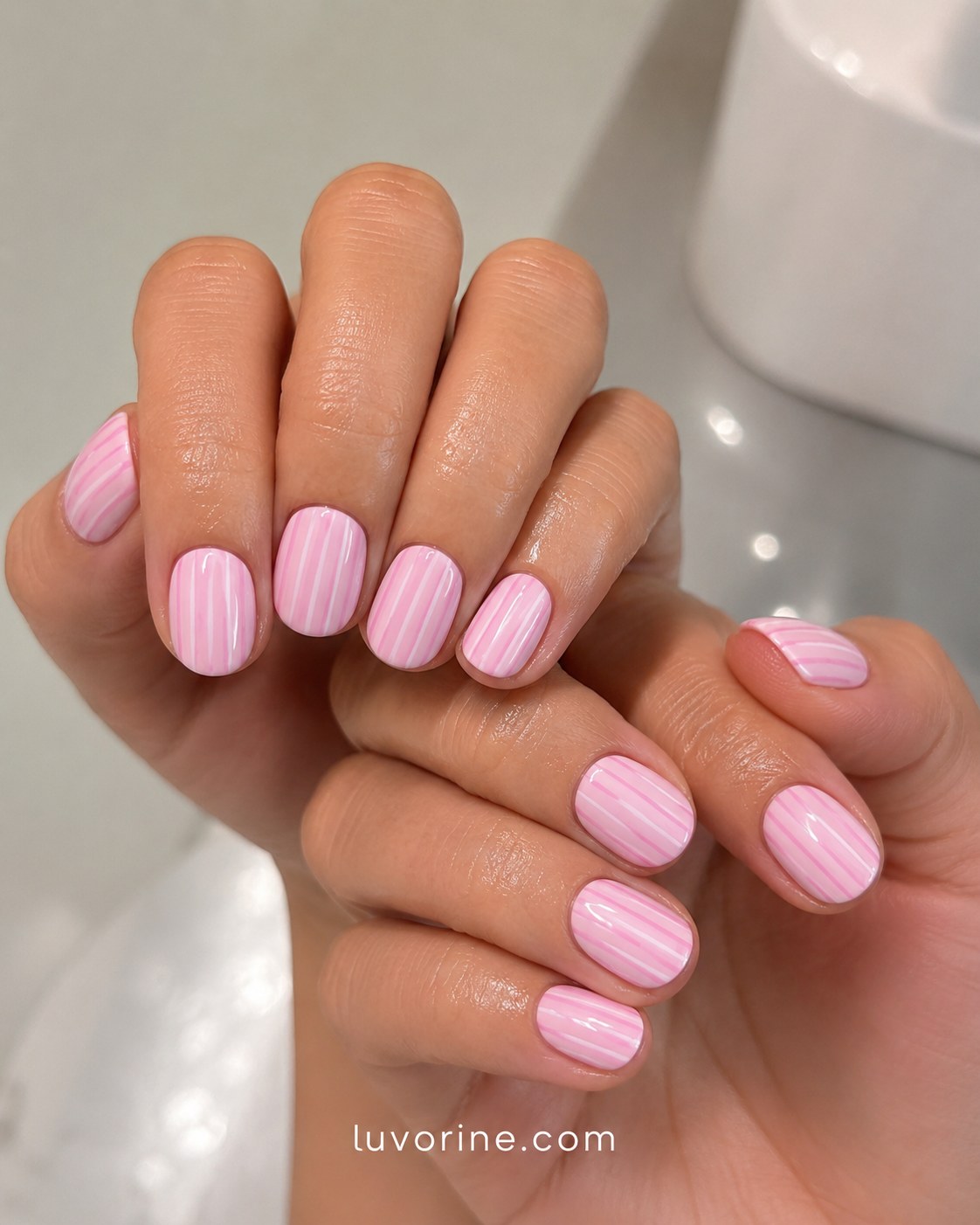 Fine vertical pinstripes covering short round pink short nails on both hands
